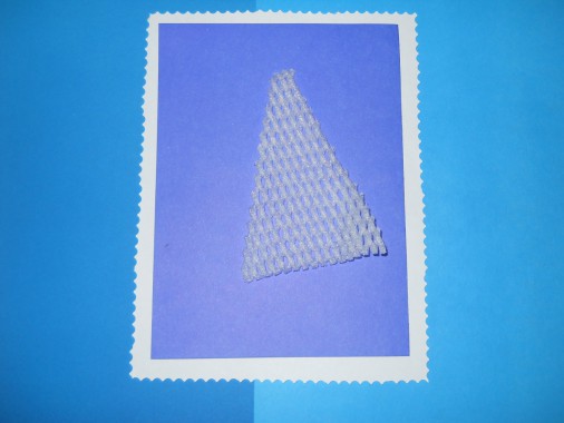 Из белой синтетической сеточки вырезаем вытянутый треугольник. Это будет крона елочки.